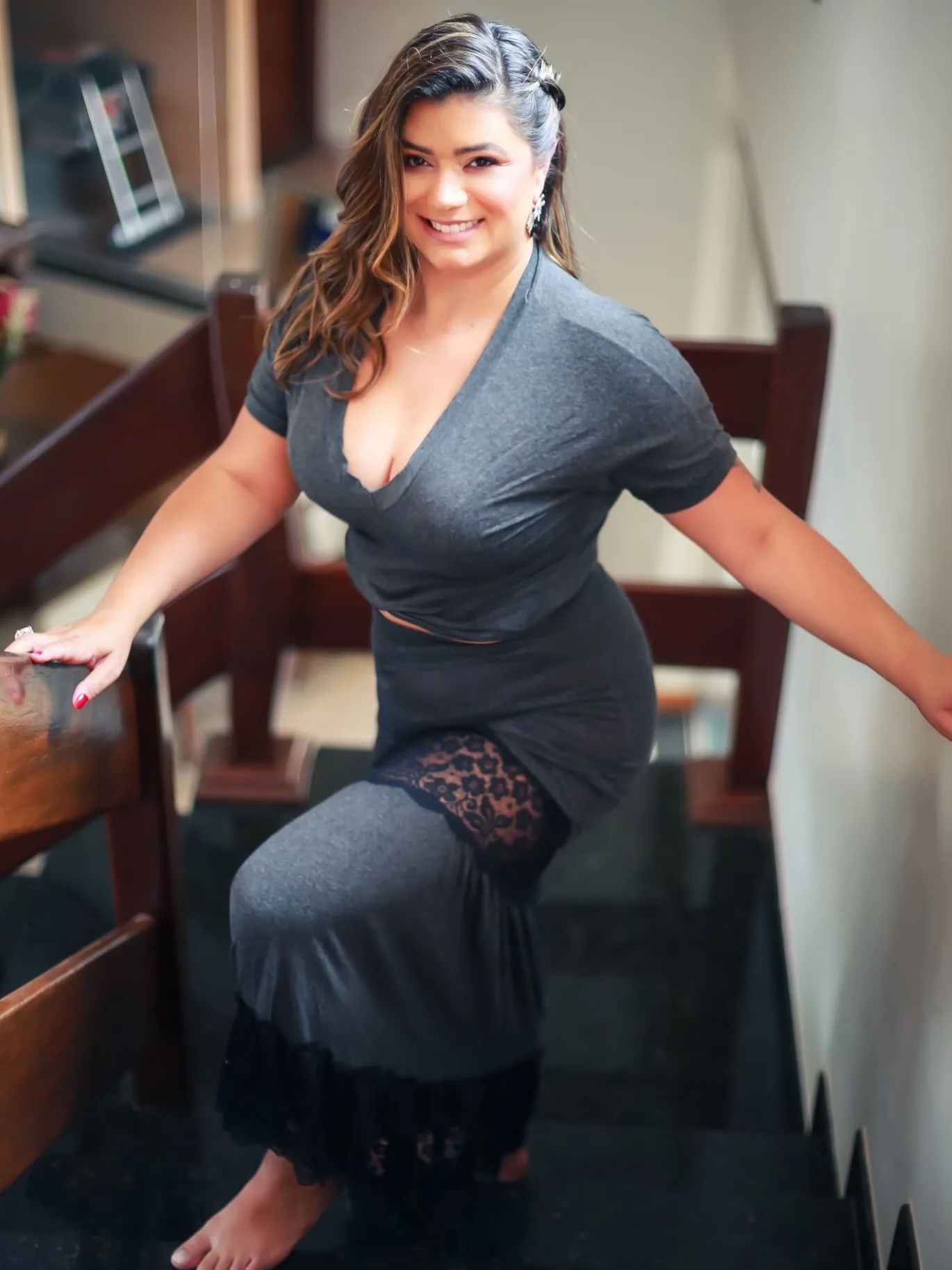 Mulher sorrindo com vestido preto junto a uma escada