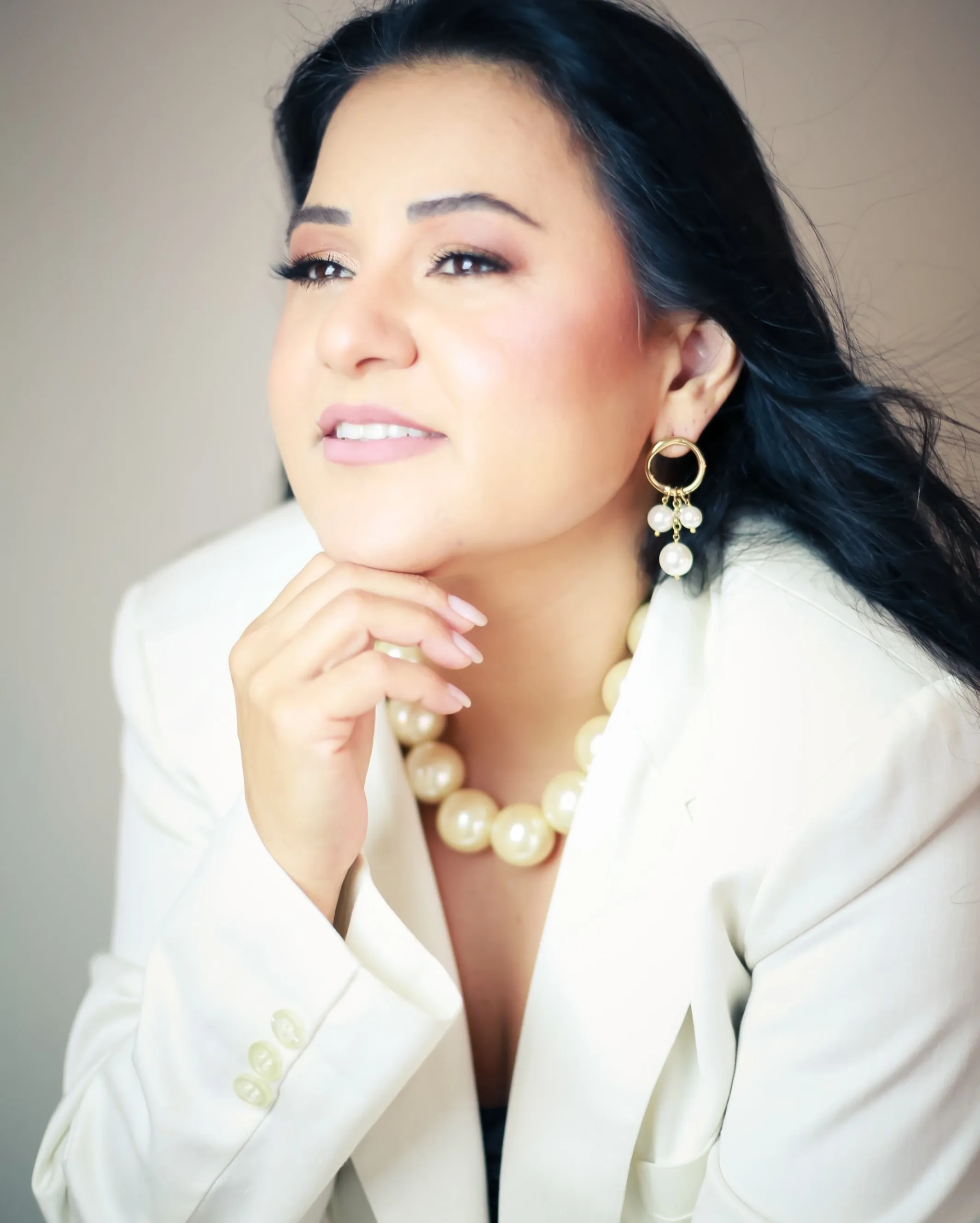 Retrato de mulher com blazer claro e a mão junto ao queixo
