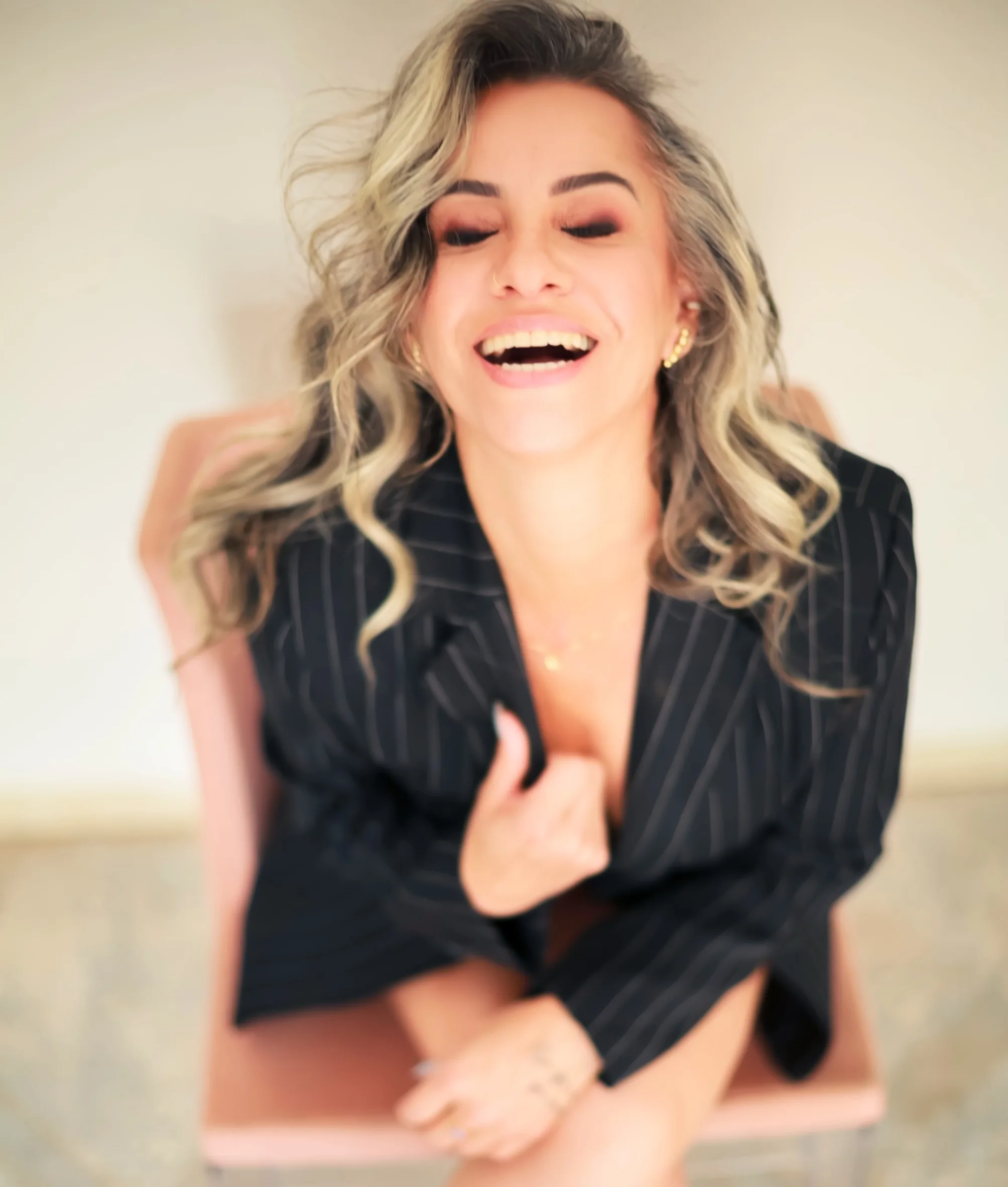 Mulher sorrindo sentada na cama, com camisa preta
