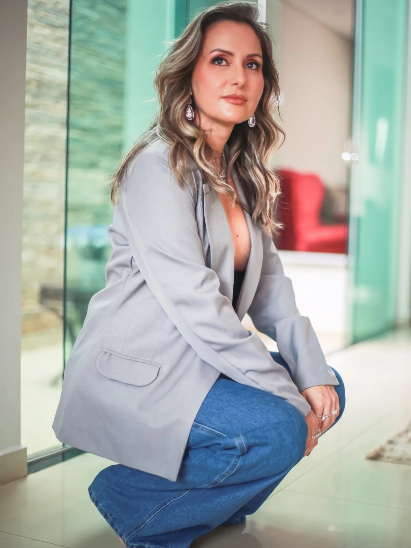 Mulher sentada com blazer cinza e calça jeans