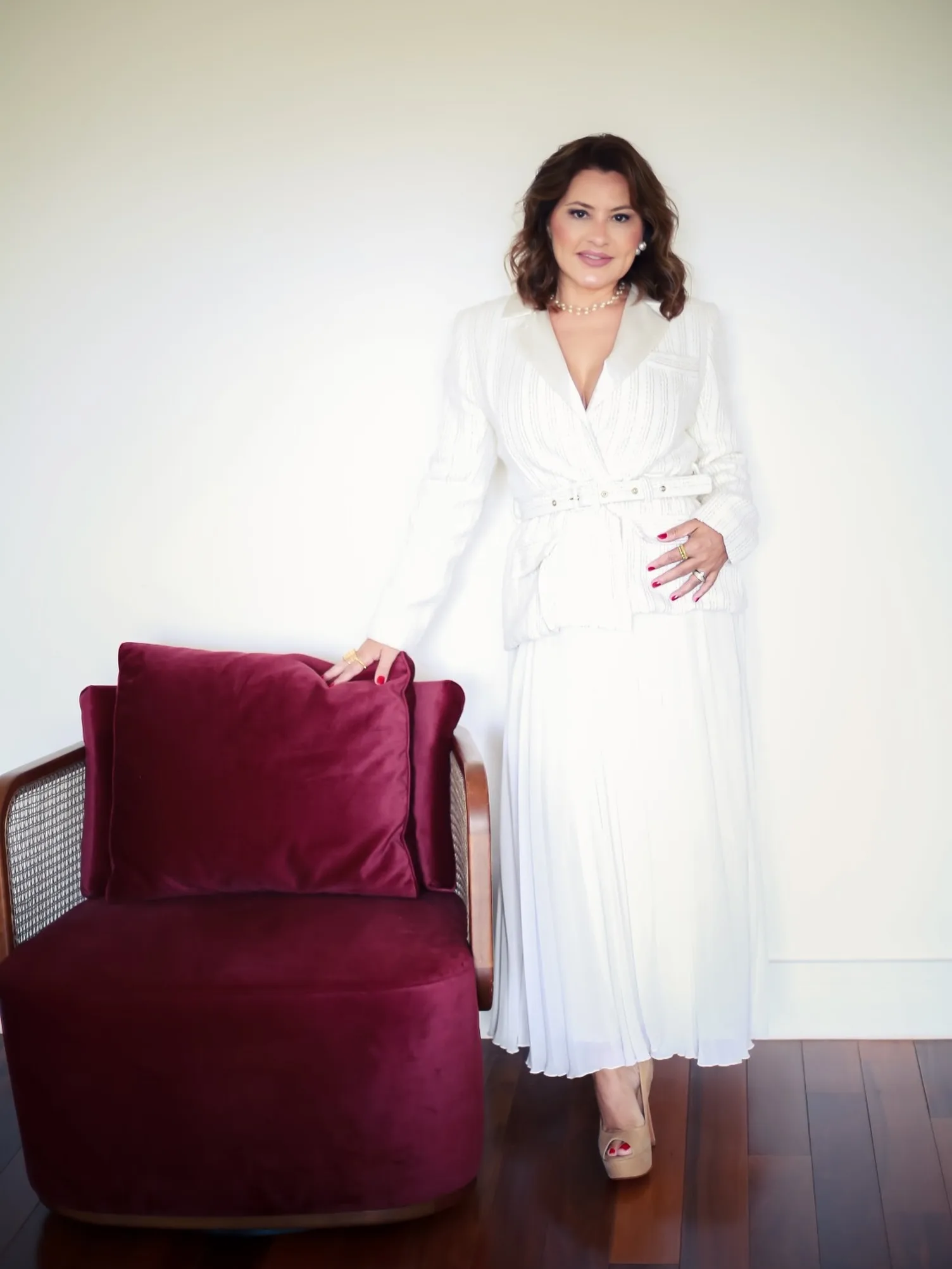 Mulher de roupa branca ao lado de uma poltrona vinho