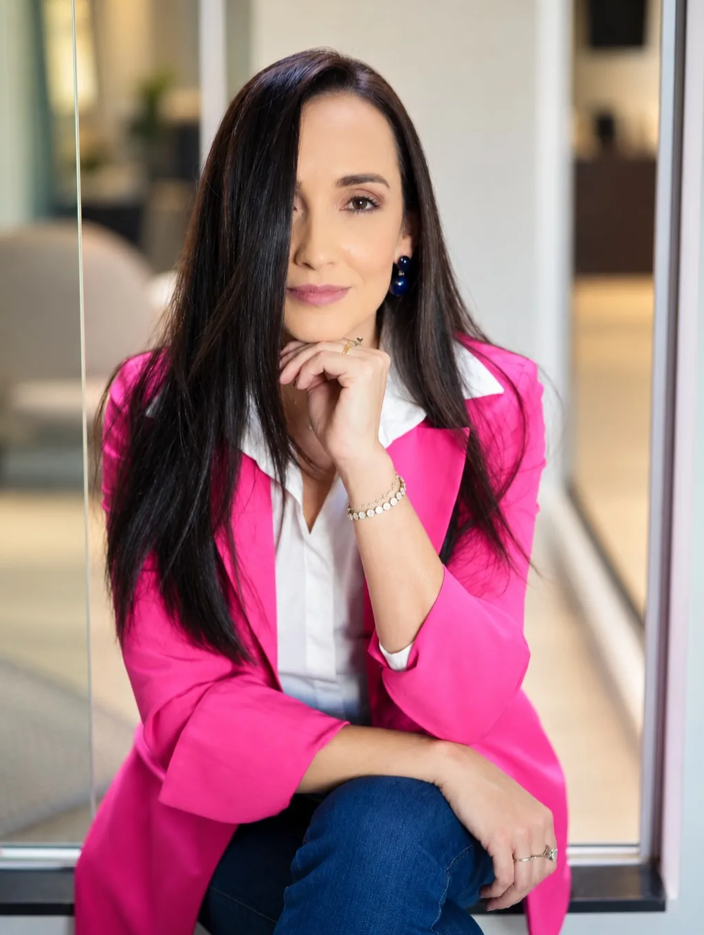 Mulher sentada com blazer rosa e calça jeans