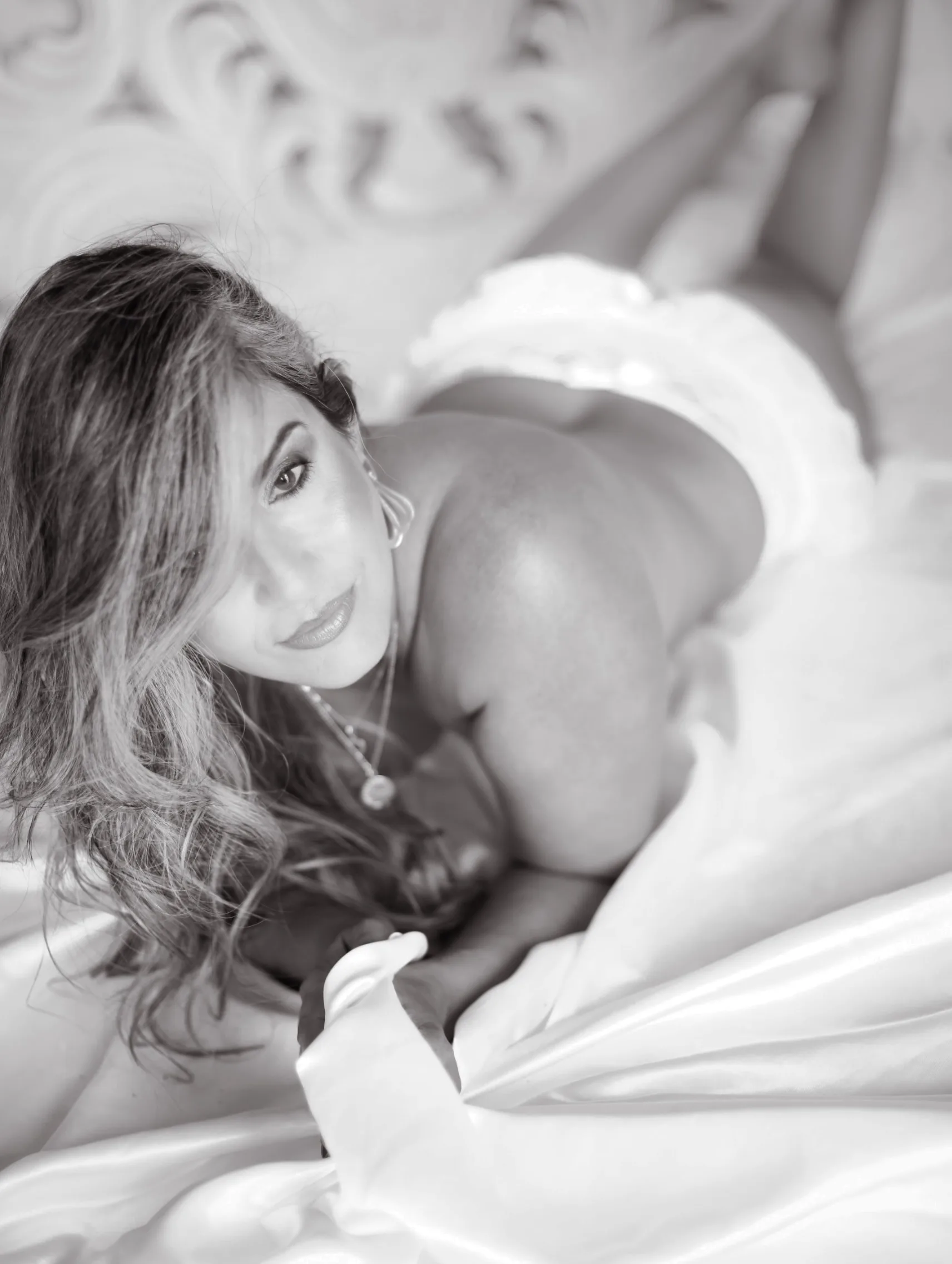 Mulher deitada sobre a cama, em fotografia em preto e branco