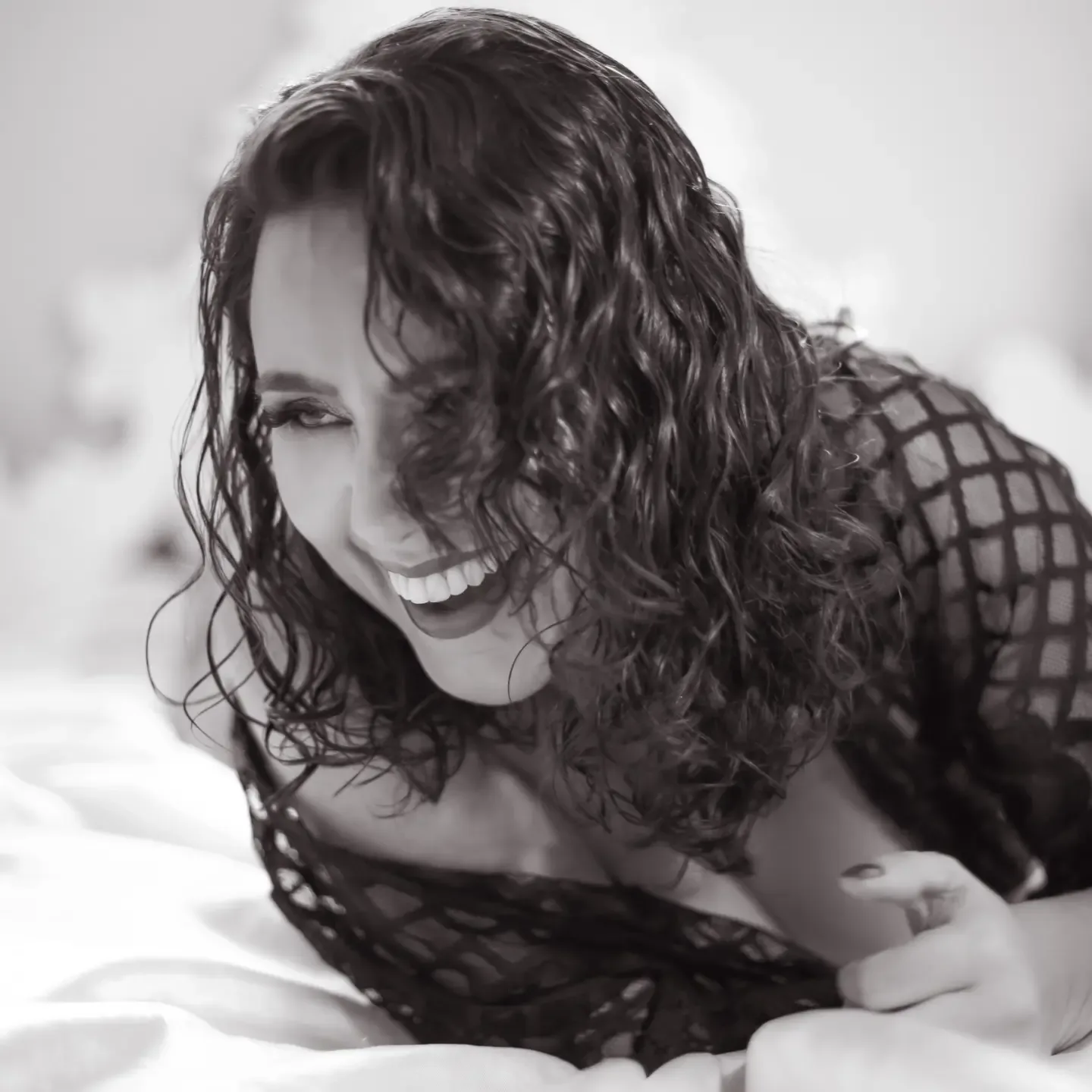 Mulher deitada com roupa escura de trama, em preto e branco