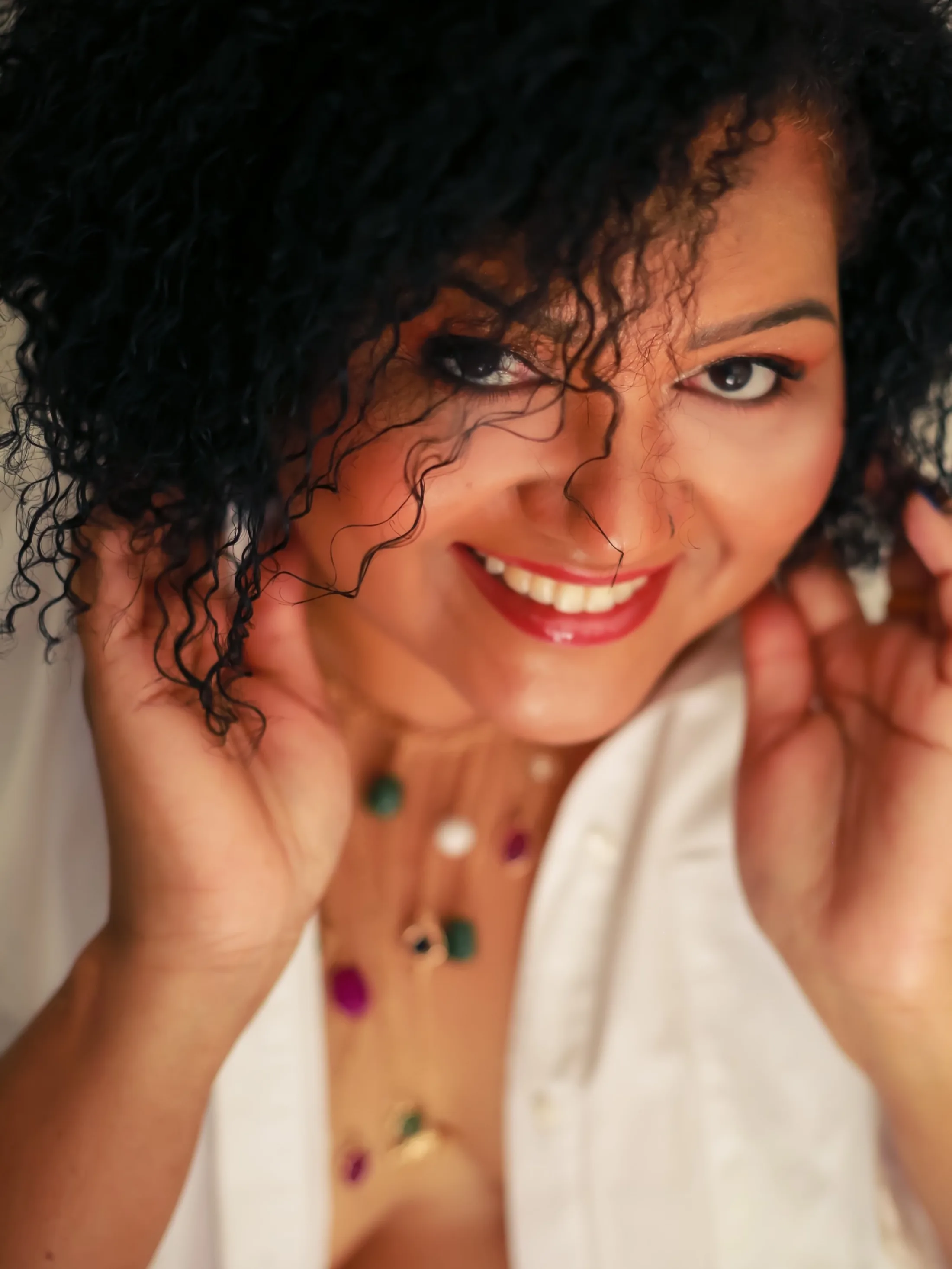 Retrato próximo de mulher sorrindo, com cabelos cacheados
