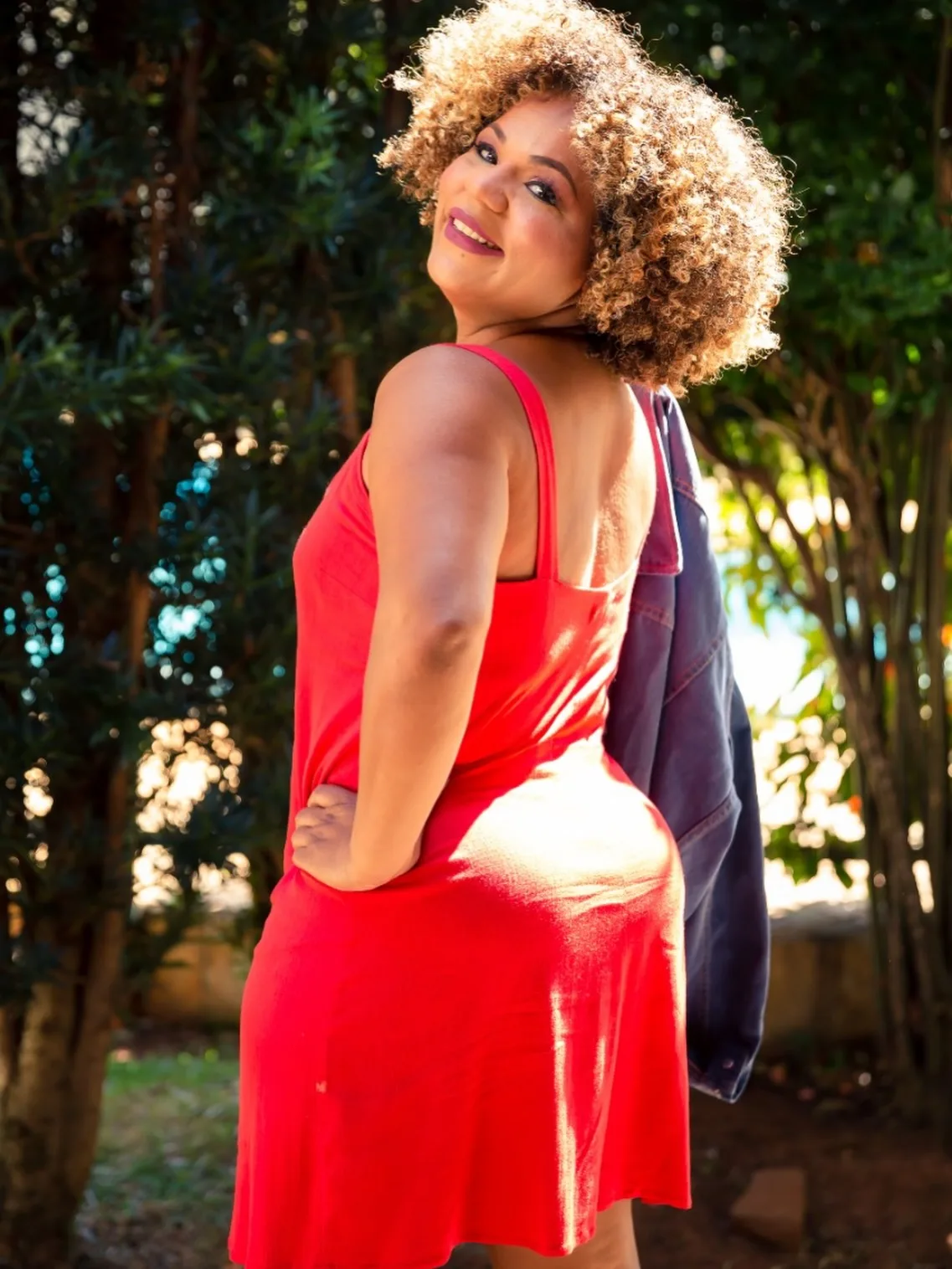 Mulher de vestido vermelho ao ar livre, olhando sobre o ombro
